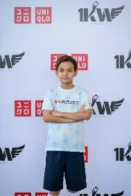 A child standing in front of a white wall with red and black logos

AI-generated content may be incorrect.